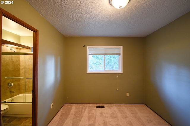 unfurnished bedroom featuring light carpet, connected bathroom, and a textured ceiling