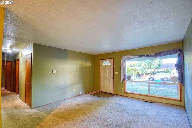 carpeted entryway with a textured ceiling