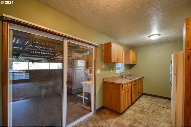 kitchen with a textured ceiling, sink, and white fridge