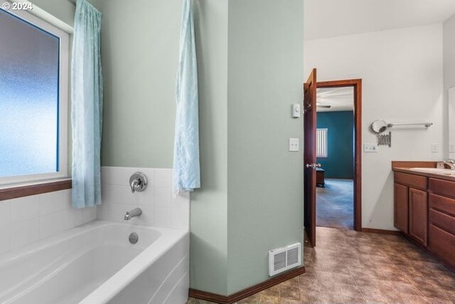 bathroom with a tub, vanity, and tile patterned flooring