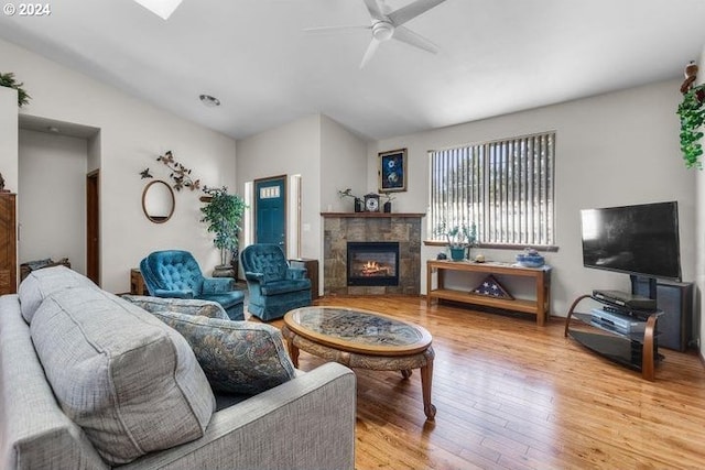 living room featuring ceiling fan, a fireplace, lofted ceiling, and wood-type flooring