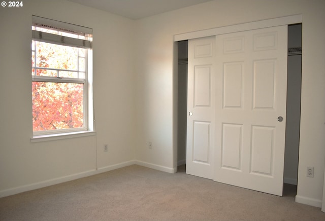 unfurnished bedroom with light colored carpet and a closet