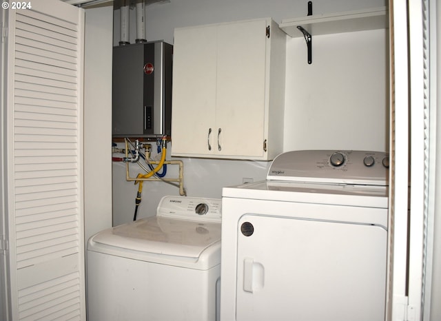 laundry area with water heater, washer and dryer, and cabinets