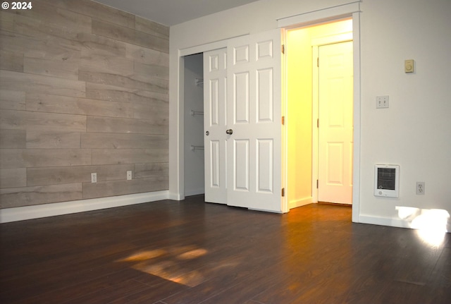 unfurnished bedroom with dark hardwood / wood-style flooring and heating unit