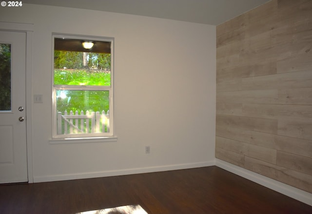 unfurnished room with dark hardwood / wood-style floors and wood walls