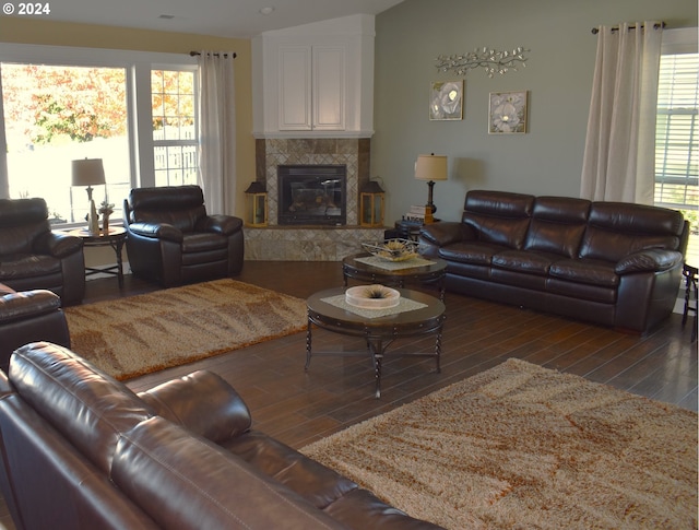 living room with a tile fireplace, dark hardwood / wood-style floors, and a healthy amount of sunlight