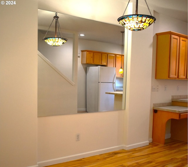 kitchen with pendant lighting, light wood-type flooring, and white fridge