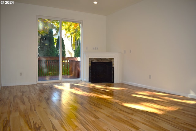 unfurnished living room featuring a stone fireplace and light wood-type flooring