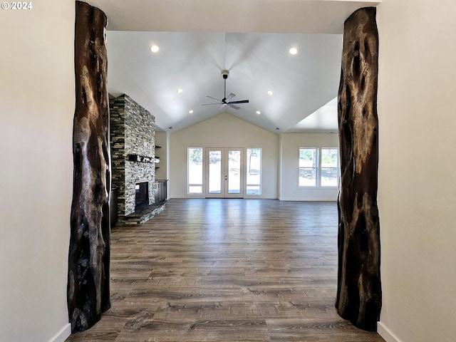 unfurnished living room featuring vaulted ceiling, ceiling fan, french doors, a fireplace, and hardwood / wood-style flooring