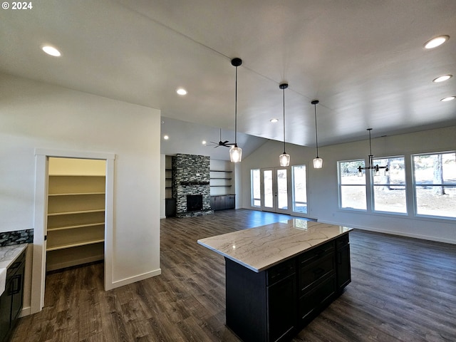 kitchen featuring dark wood-type flooring, pendant lighting, and a stone fireplace