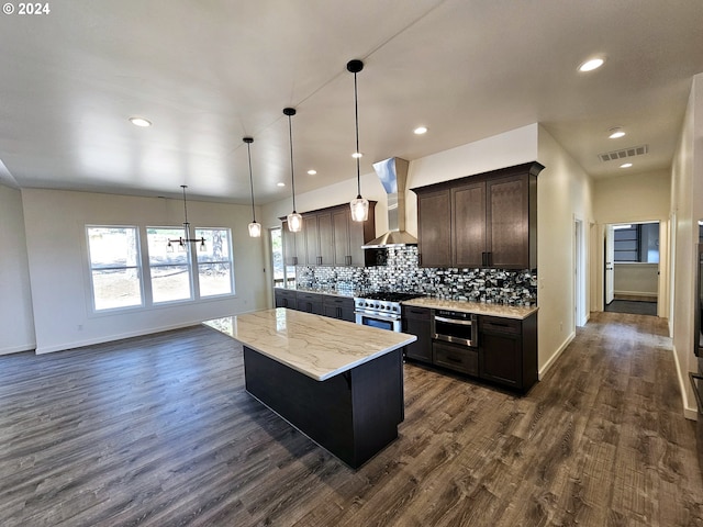 kitchen with stainless steel stove, wall chimney range hood, pendant lighting, and dark wood-type flooring