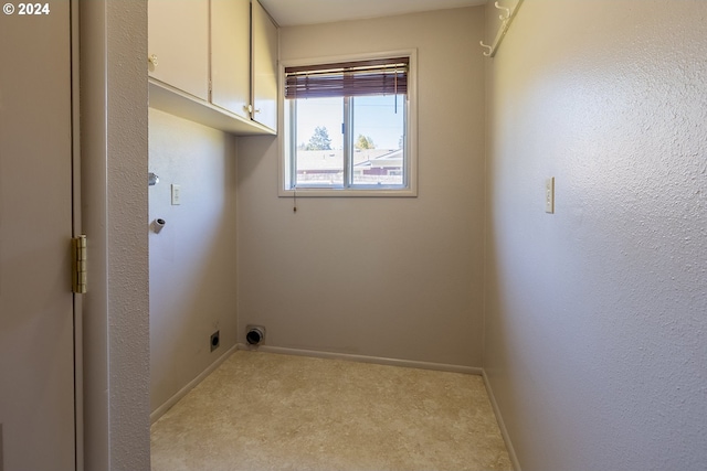 laundry room featuring electric dryer hookup, cabinets, and light colored carpet