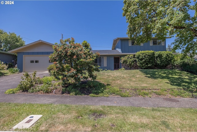 view of property hidden behind natural elements with a garage and a front yard