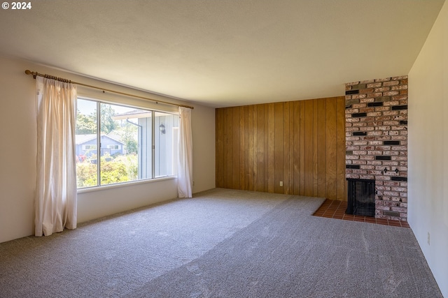 unfurnished living room featuring dark carpet, a wood stove, and wood walls