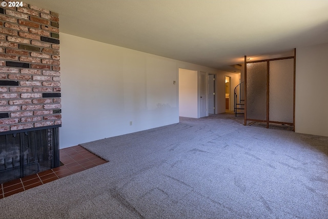 unfurnished living room with dark carpet and a brick fireplace