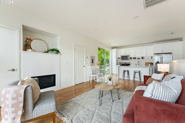 living room featuring sink and light hardwood / wood-style flooring