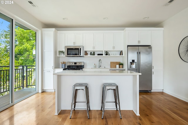 kitchen with appliances with stainless steel finishes, plenty of natural light, white cabinets, and light wood-type flooring