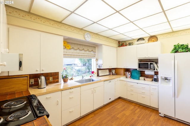 kitchen with decorative backsplash, white cabinets, light hardwood / wood-style flooring, sink, and white appliances