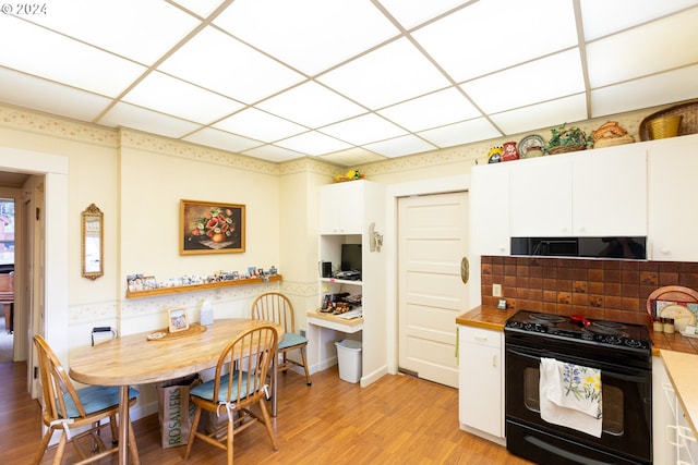 kitchen with black range with electric cooktop, a paneled ceiling, light hardwood / wood-style floors, and white cabinets