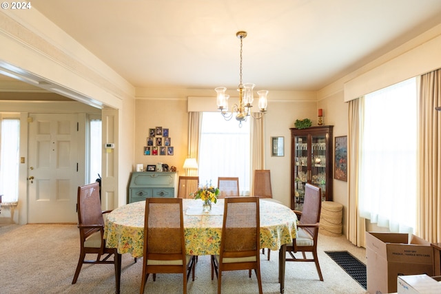 carpeted dining space featuring a notable chandelier and a healthy amount of sunlight