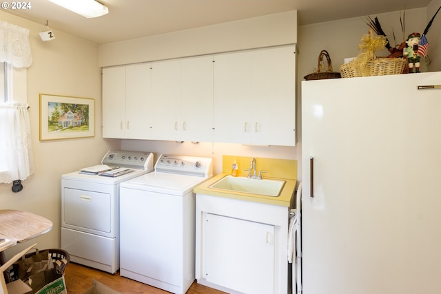 laundry room featuring cabinets, light hardwood / wood-style flooring, sink, and washing machine and dryer