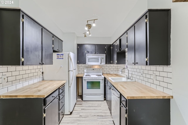 kitchen with butcher block counters, sink, white appliances, and light hardwood / wood-style floors