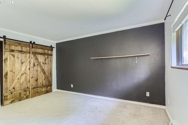 unfurnished bedroom featuring a barn door, carpet flooring, and crown molding