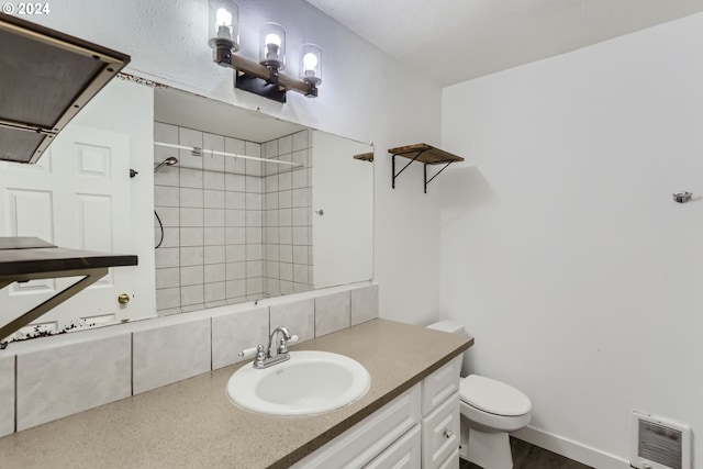 bathroom with vanity, tiled shower, heating unit, and toilet