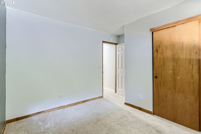 unfurnished bedroom with light colored carpet and a closet