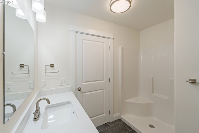 bathroom with tile patterned flooring, vanity, and walk in shower