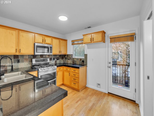 kitchen with sink, stainless steel appliances, plenty of natural light, and light hardwood / wood-style flooring