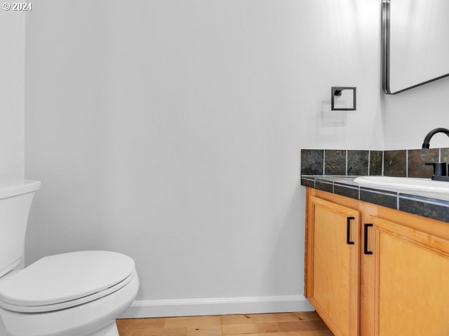 bathroom with hardwood / wood-style floors, vanity, and toilet