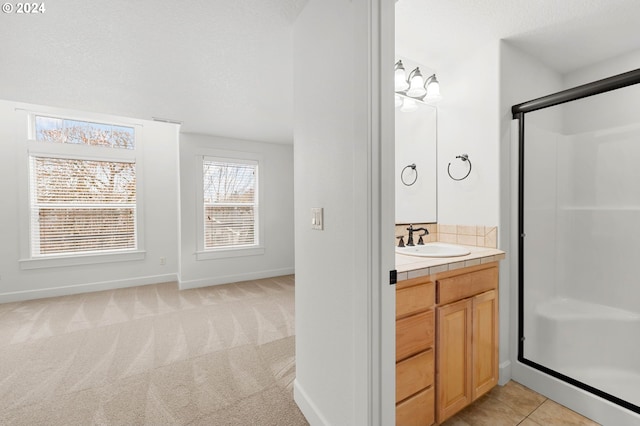 bathroom with a shower with shower door, tile patterned flooring, and vanity