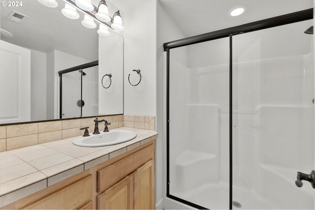 bathroom with backsplash, a textured ceiling, vanity, and walk in shower