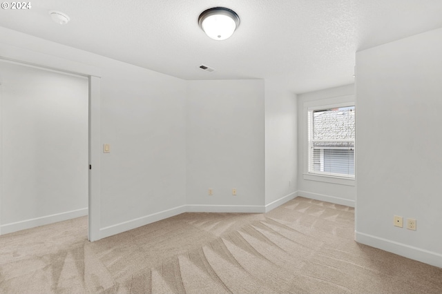 carpeted empty room featuring a textured ceiling