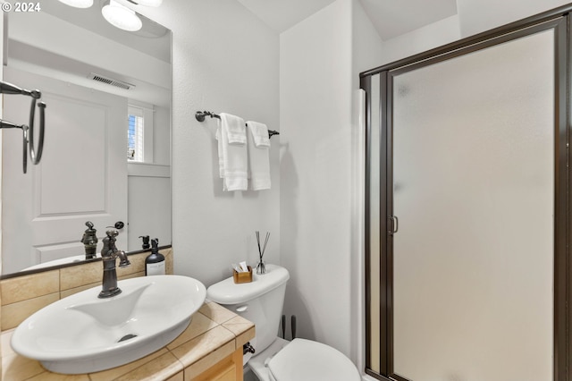 bathroom with toilet, vanity, and a shower with shower door