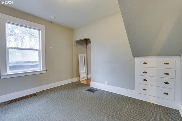 bonus room with vaulted ceiling and carpet flooring