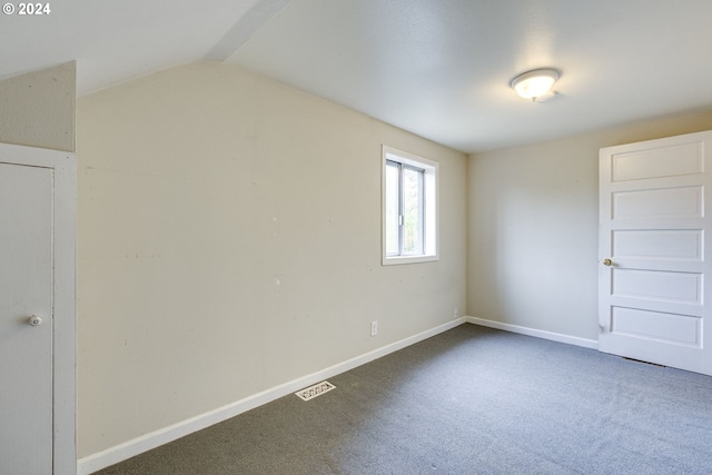 interior space featuring vaulted ceiling and dark carpet