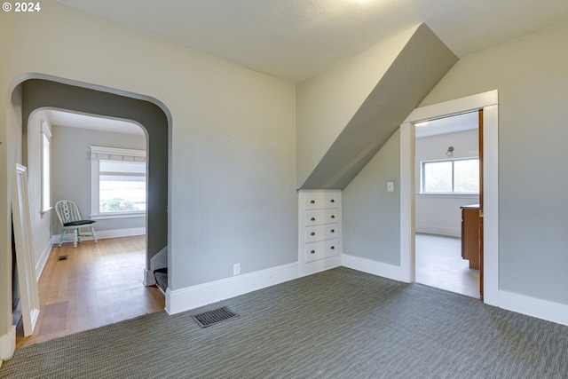 bonus room featuring a healthy amount of sunlight and dark colored carpet