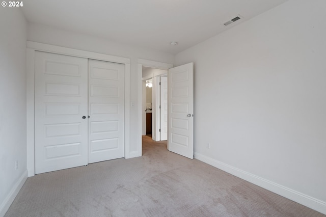 unfurnished bedroom featuring light colored carpet and a closet