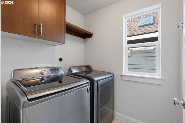 laundry room with washing machine and dryer, light tile patterned flooring, and cabinets