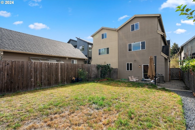 rear view of property featuring a yard, a patio area, and central air condition unit