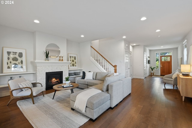 living room with a stone fireplace and dark hardwood / wood-style floors