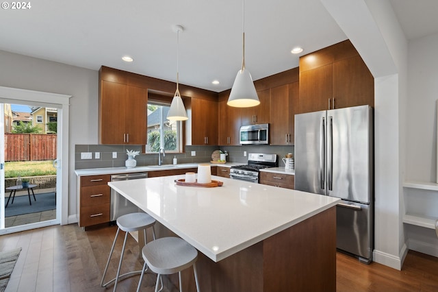 kitchen with appliances with stainless steel finishes, hanging light fixtures, dark wood-type flooring, and plenty of natural light