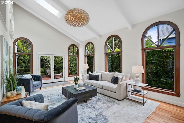 living room with light hardwood / wood-style floors, a skylight, high vaulted ceiling, and french doors