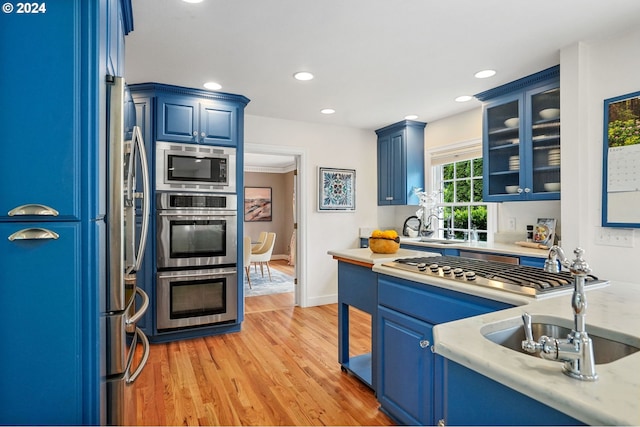 kitchen featuring sink, blue cabinets, stainless steel appliances, and light hardwood / wood-style flooring