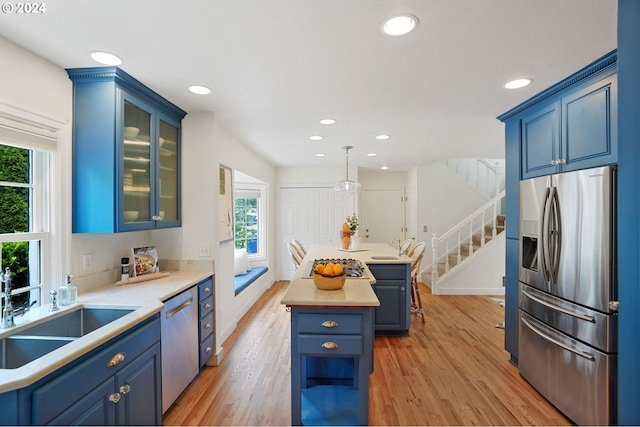 kitchen featuring appliances with stainless steel finishes, a center island, decorative light fixtures, and blue cabinets