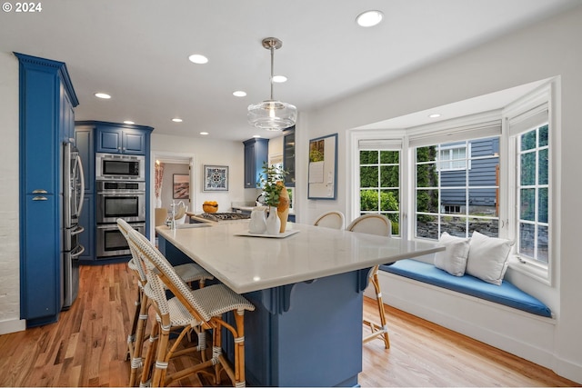 kitchen with stainless steel appliances, blue cabinets, kitchen peninsula, pendant lighting, and a breakfast bar