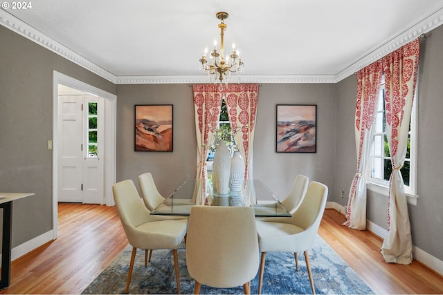 dining space with hardwood / wood-style floors, crown molding, and a notable chandelier