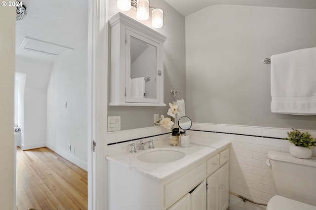 bathroom with vanity, hardwood / wood-style flooring, tile walls, toilet, and lofted ceiling